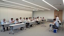 二列に並べられた机の前に座る参加者と、その手前に置かれた机の前の椅子に座る代表者たちの写真