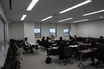 会議室で黒い机を囲んで会議を行っている様子の写真