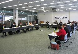 長机をU字型に配置している所に多数の人が椅子に座って会議をしている様子の写真