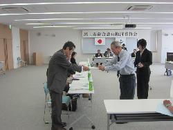 委託状を手渡ししている石川市長とそれを両手で受け取る委員の様子の写真