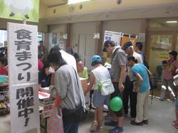 「食育まつり開催中」の看板が立てられた食菜館前ロビーに人が賑わっている写真