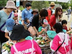 来場者の親子たちが量りに乗った野菜の重さを考えている写真